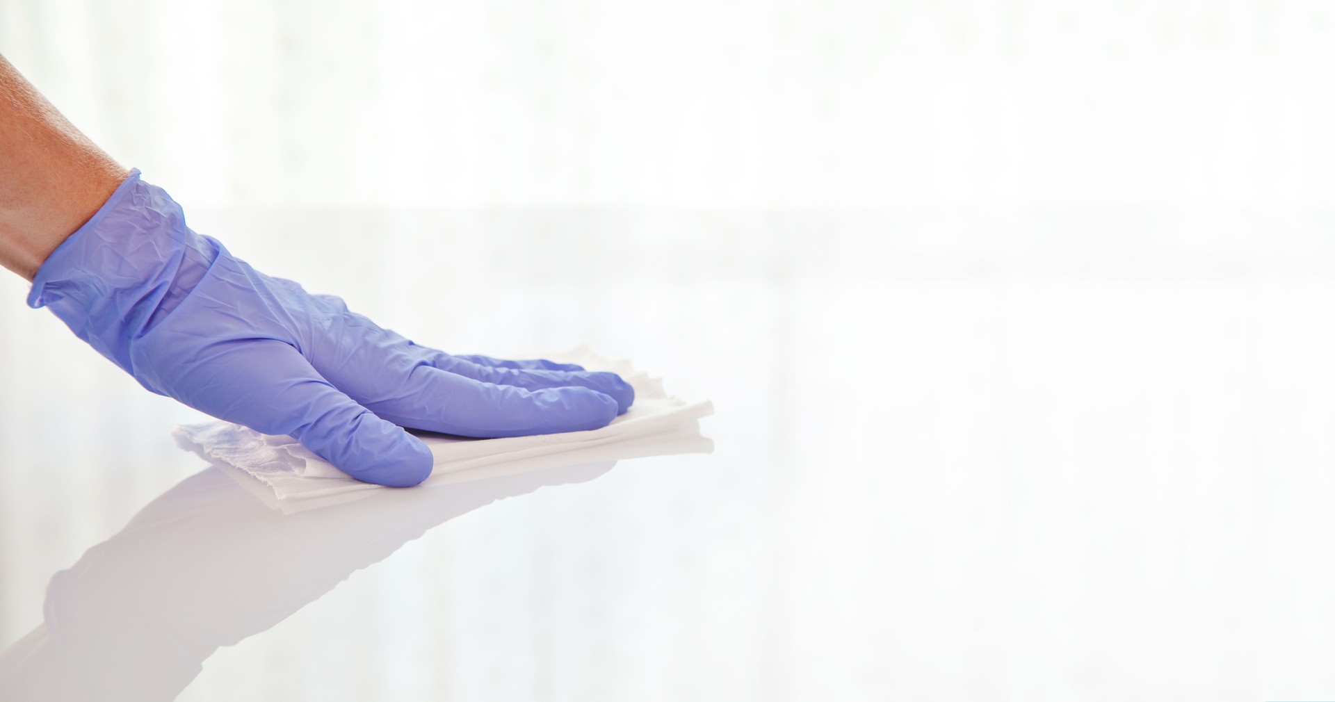 Surface disinfecting home cleaning with sanitizing antibacterial wipes protection against COVID-19 spreading wearing medical blue gloves.